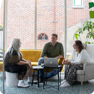 Overlegmoment tussen Mark, Kayleigh en Petra in een informele vergaderruimte