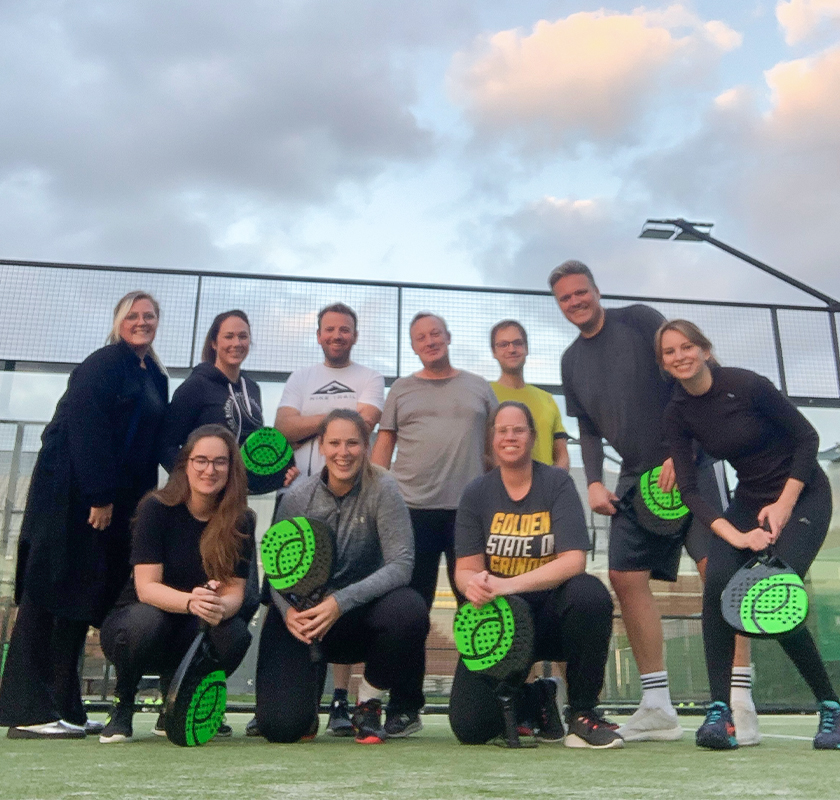 Onest teamuitje poserend na padelwedstrijd.