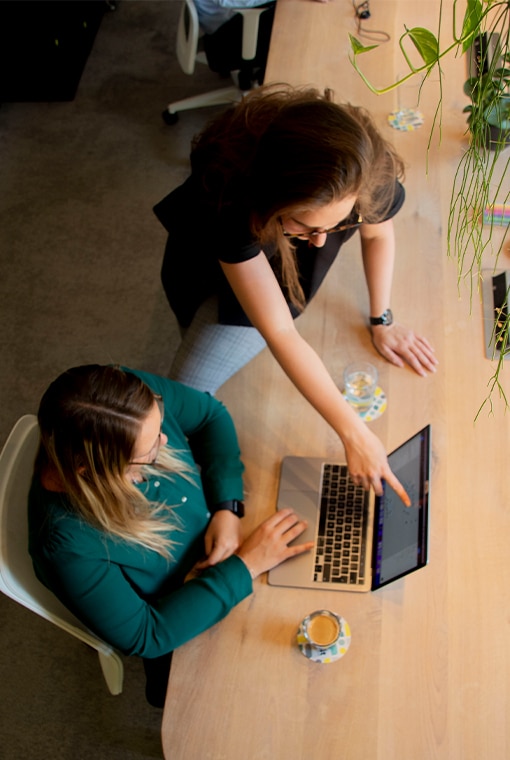 Sandra Buitendijk en Cynthia van Steenvelt werkend aan de tafel in het kantoor van online marketingbureau Onest.